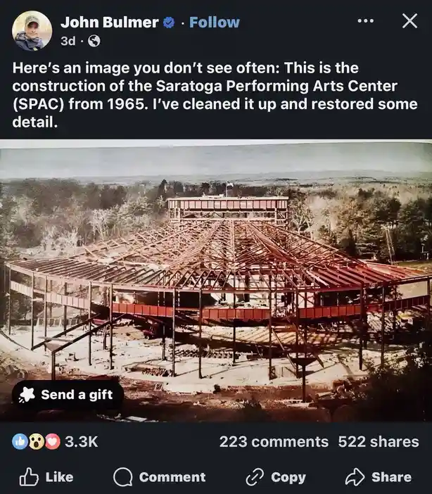 A vintage, restored photograph shows the skeletal steel frame of the Saratoga Performing Arts Center (SPAC) under…