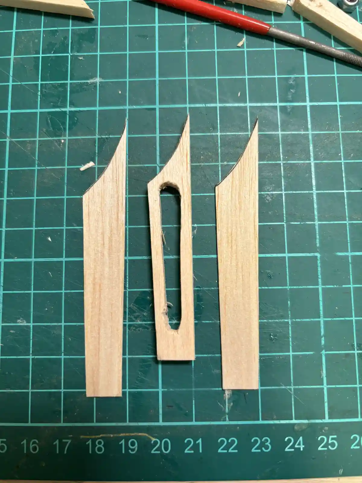 Three wooden pieces arranged on a green grid mat to visually resemble the number 11, with the middle piece having a cutout…