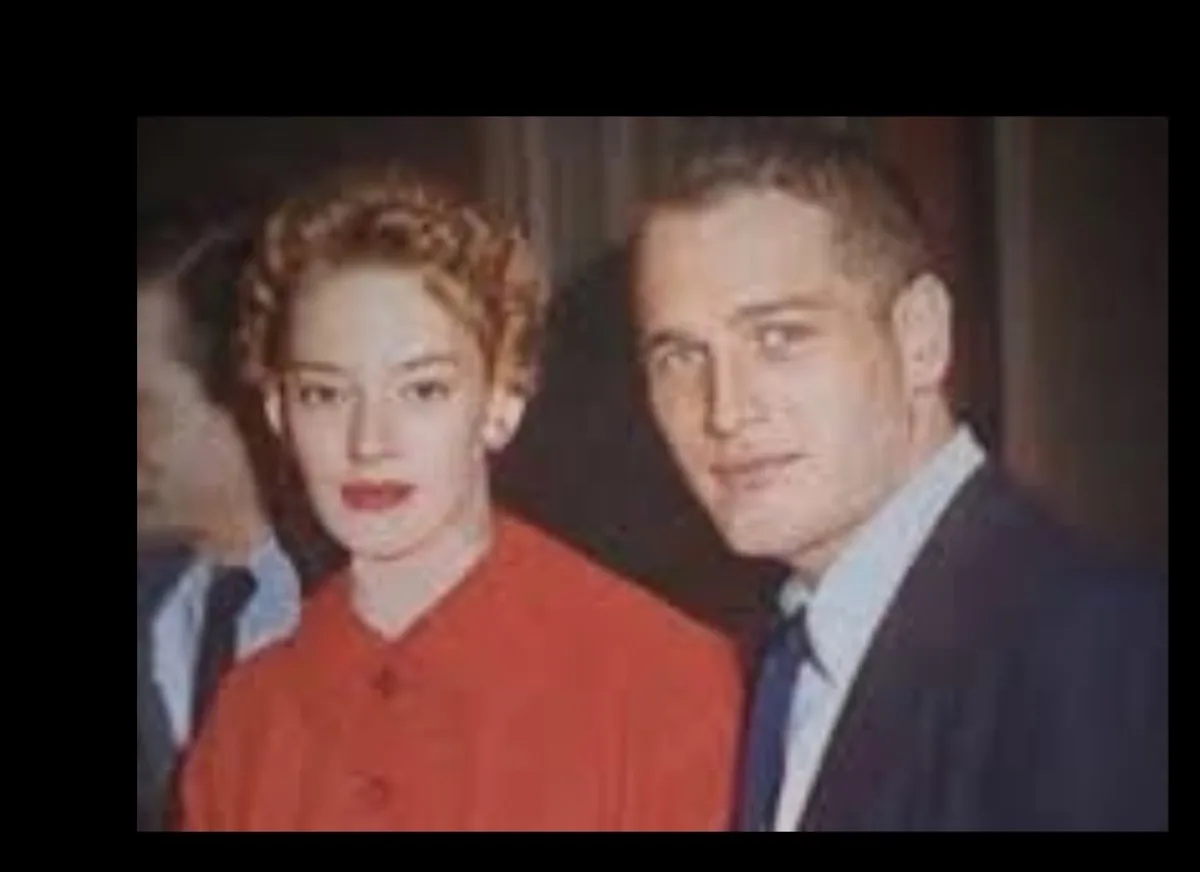 A vintage photo shows a man and woman posing together; the woman wears a red dress and the man wears a suit. Overlaid text…