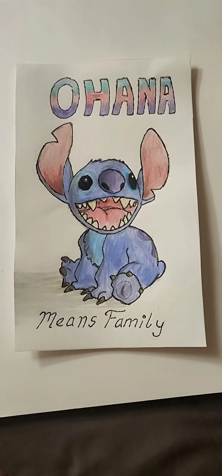 A hand-drawn illustration of Stitch from Lilo & Stitch sitting with a wide, toothy grin. Above him, the word 'OHANA' is…