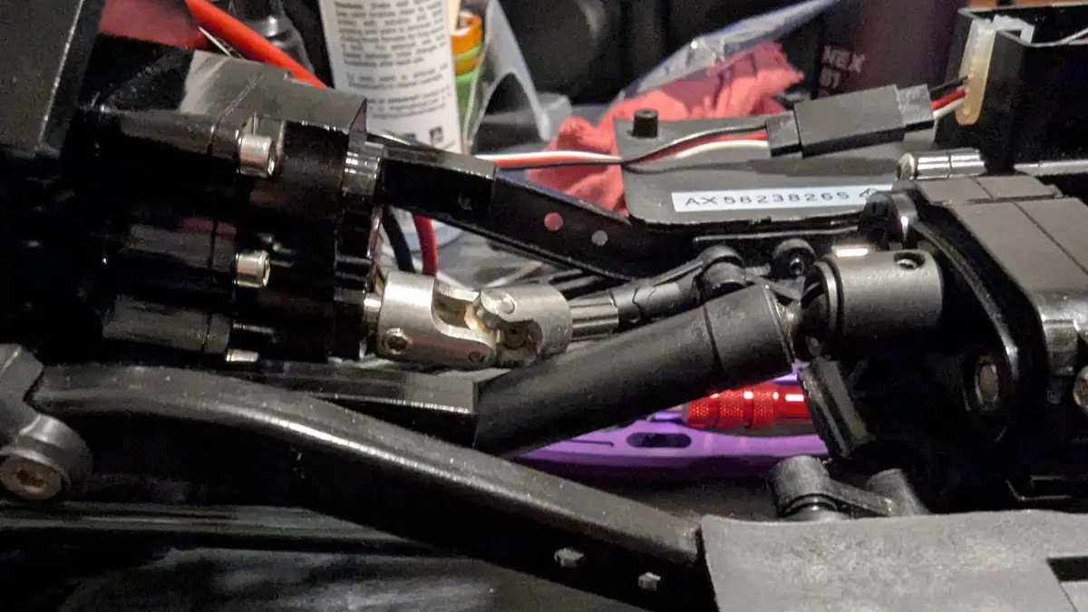 A close-up photo of a complex, disassembled mechanical device with black and silver parts, wires, and a purple tool in the…