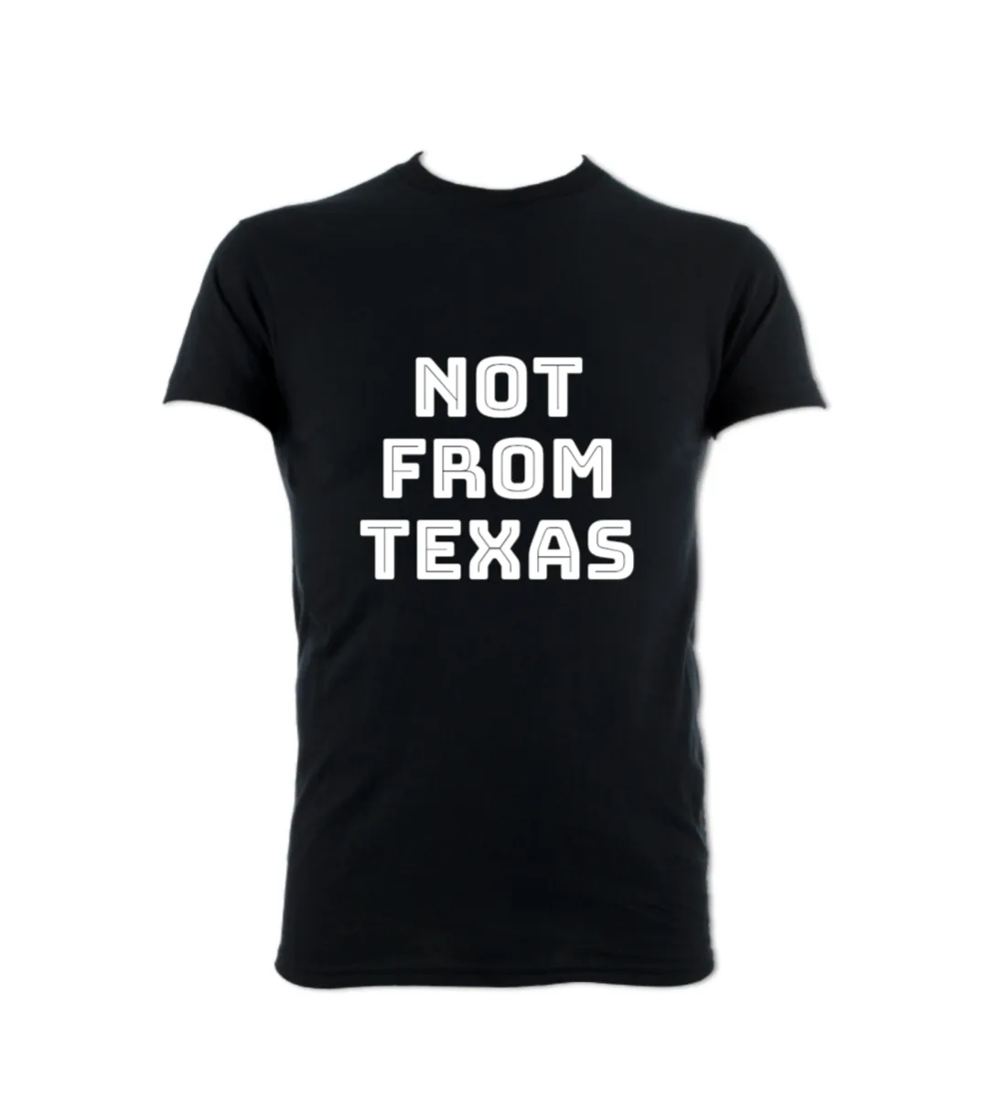 A plain black t-shirt with bold white text centered on the chest that reads 'NOT FROM TEXAS' in three lines. The shirt is…