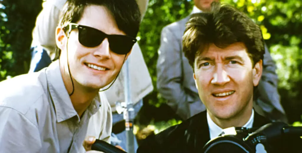 Two men are pictured outdoors, one wearing sunglasses and smiling, the other looking slightly concerned while holding a…