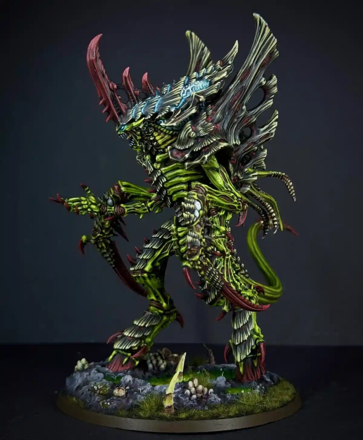 A highly detailed, painted miniature of a grotesque, biomechanical creature with green, skeletal, and organic features, red…
