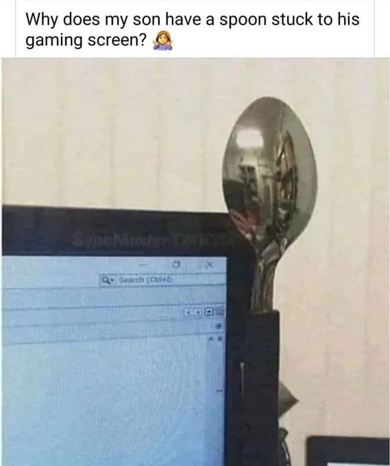 A close-up photo shows a large metal spoon magnetically adhered to the top right corner of a computer monitor displaying a…