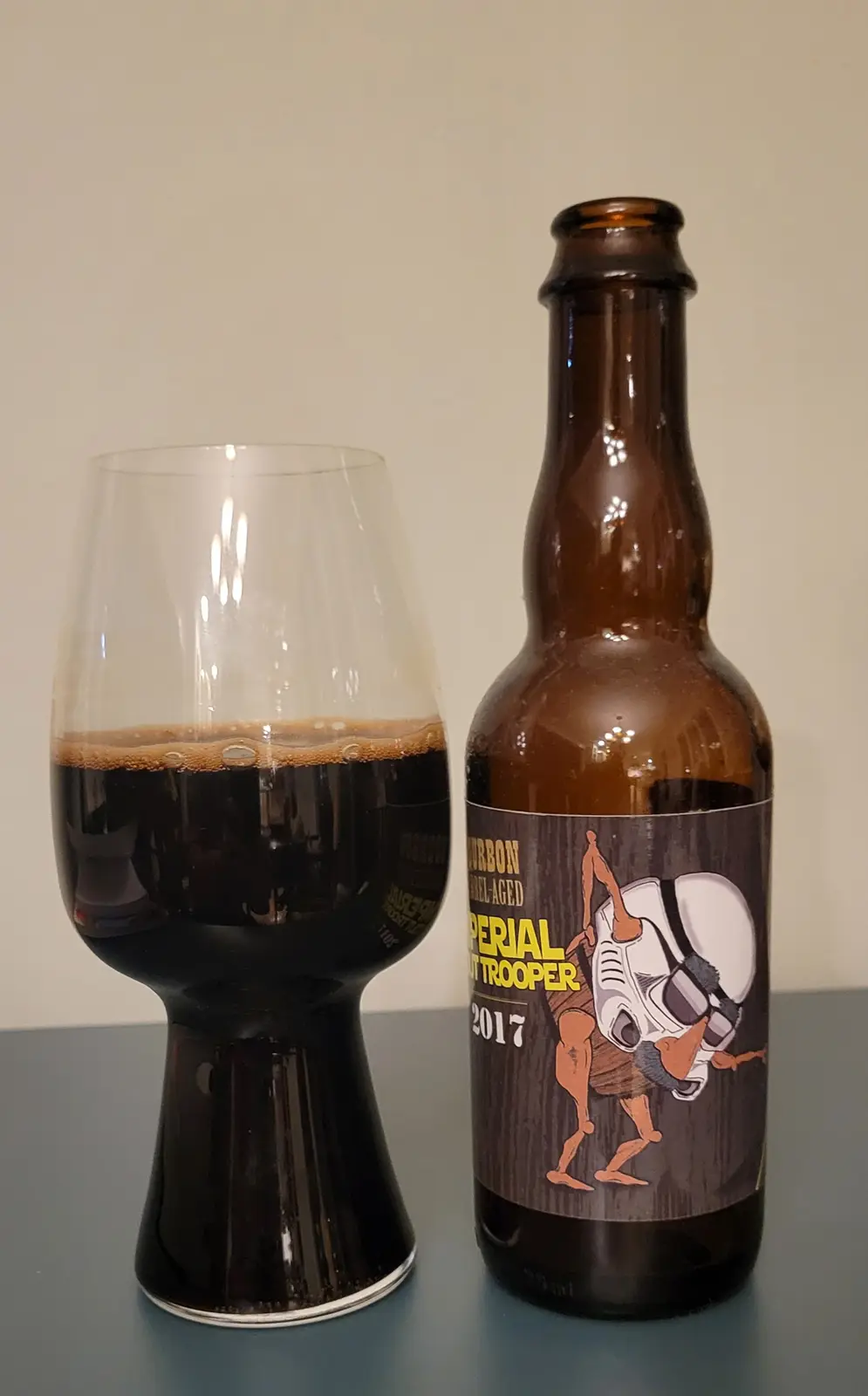A brown beer bottle labeled 'Bourbon Barrel-Aged Imperial Slut Trooper 2017' with a cartoon trooper on the label stands next…