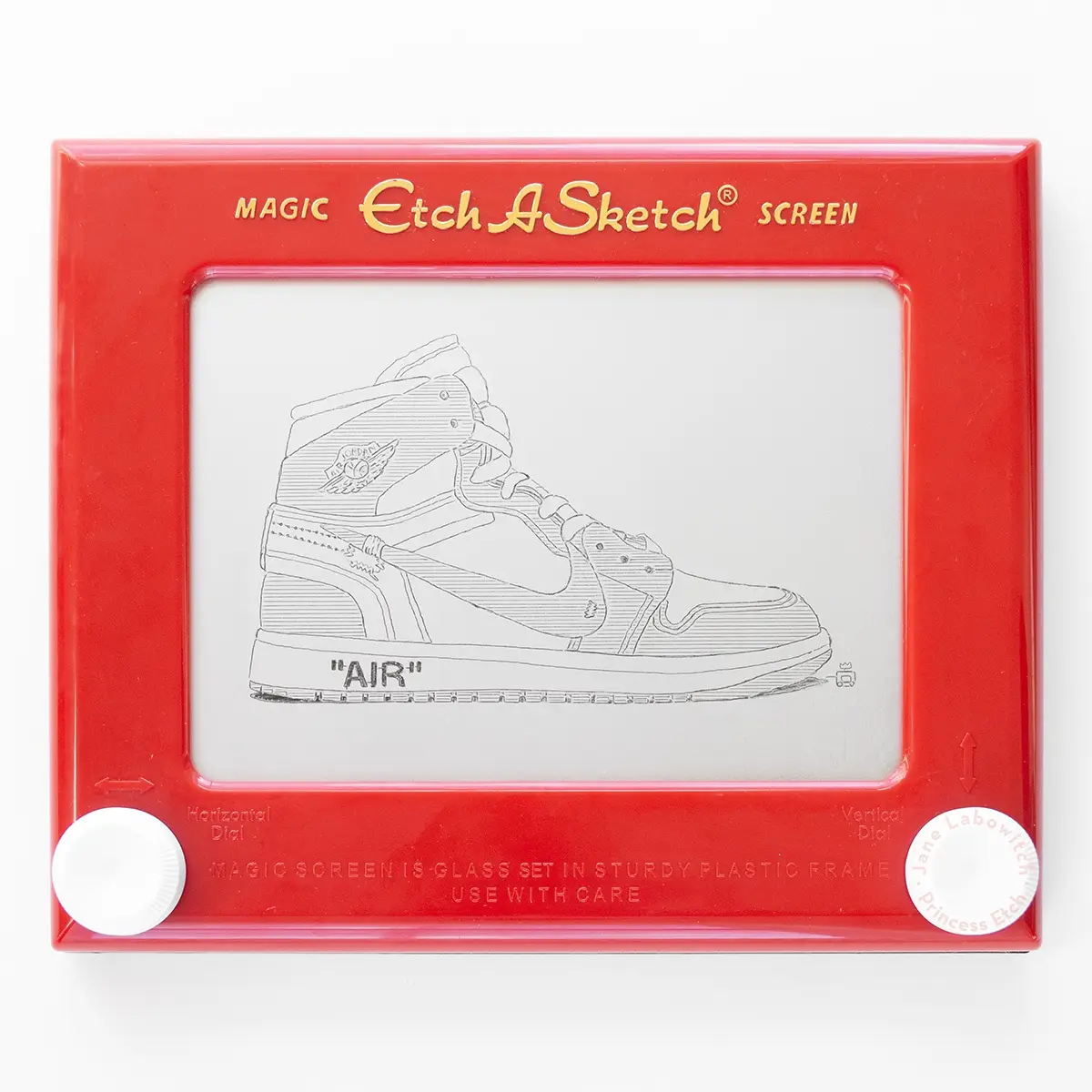 A red Etch A Sketch toy displays a detailed line drawing of a high-top sneaker, specifically a Jordan 1, with the word 'AIR'…