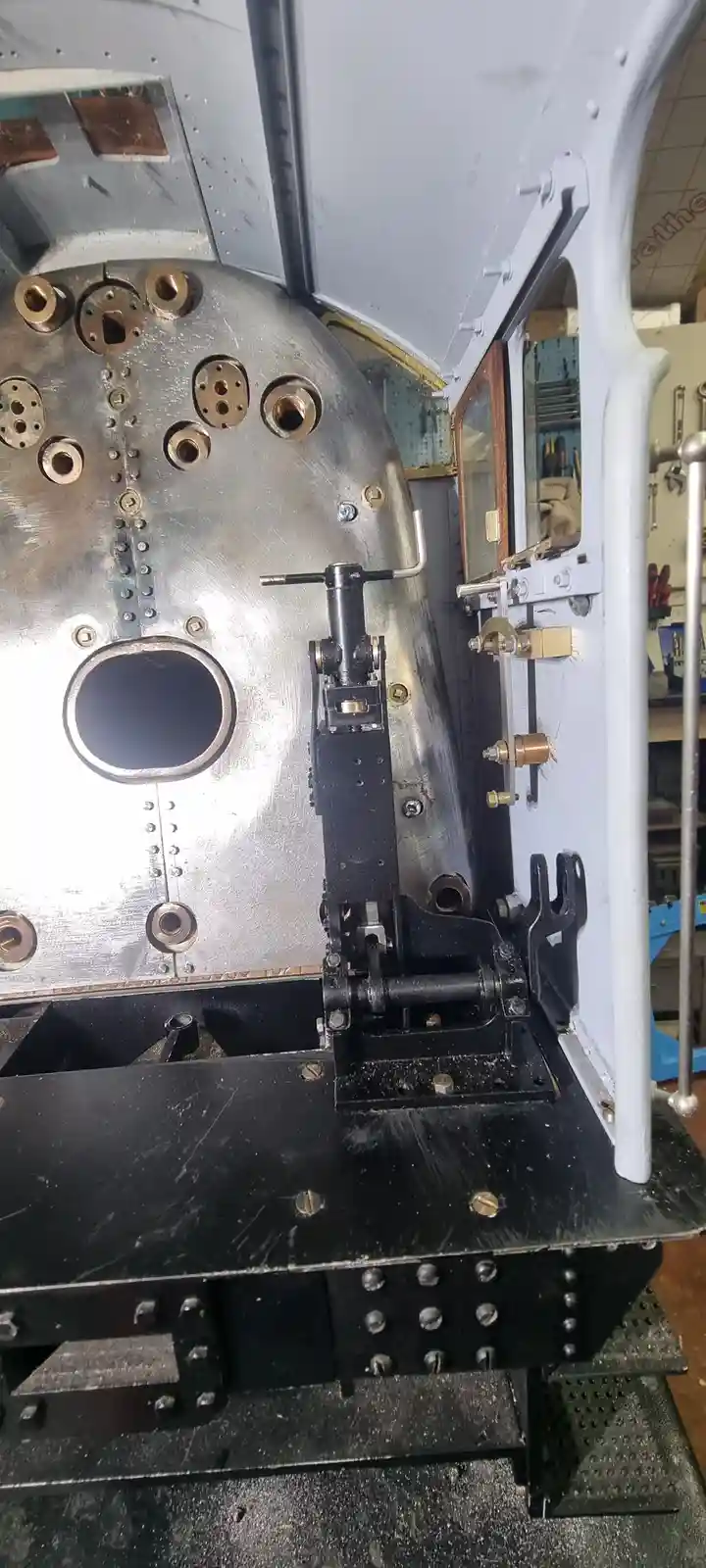 A close-up photo of the exposed internal components of a steam locomotive's boiler, showing riveted metal plates, brass…