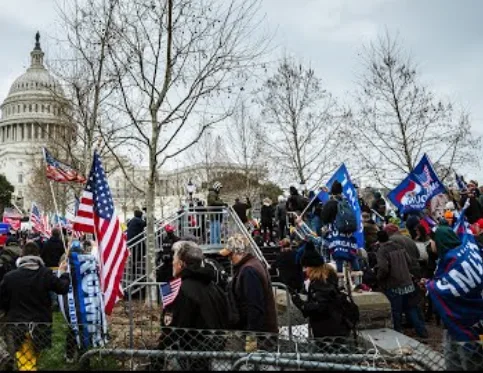 A crowd of people holding American flags and blue signs with 'we are the 99%' text stands outside the U.S. Capitol building…
