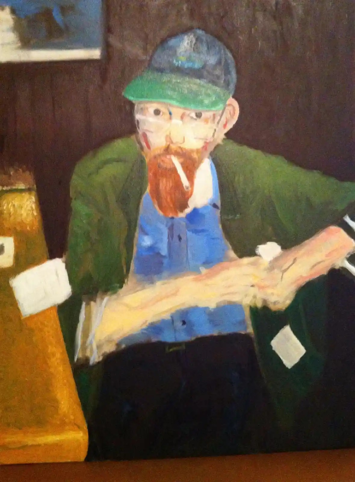 A painting depicts a man with a red beard, wearing a green cap and glasses, sitting with a cigarette in his mouth and…
