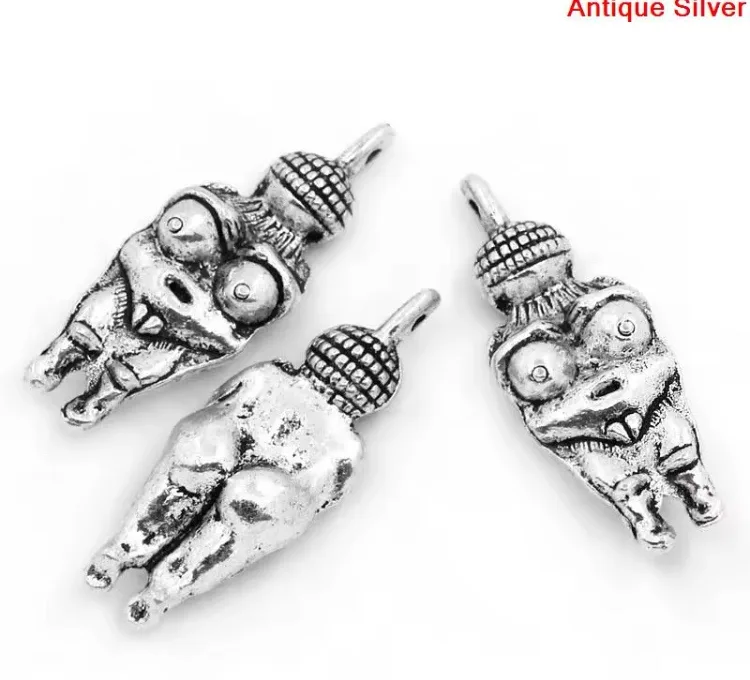 Three antique silver charms shaped like grotesque, cartoonish figures with large eyes and open mouths, arranged on a white…