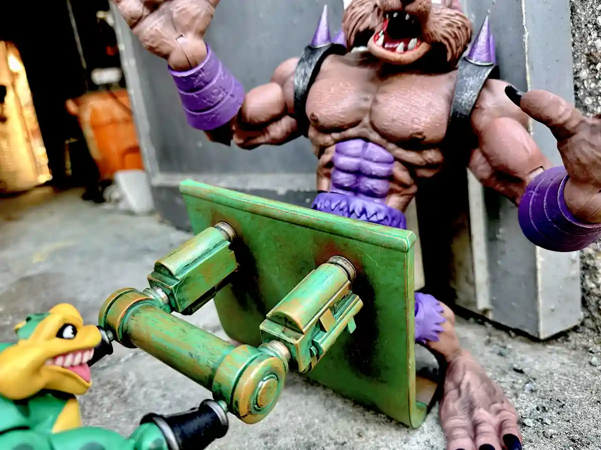 A muscular, brown-furred, purple-accented action figure with a fierce expression and spiked shoulder pads stands behind a…