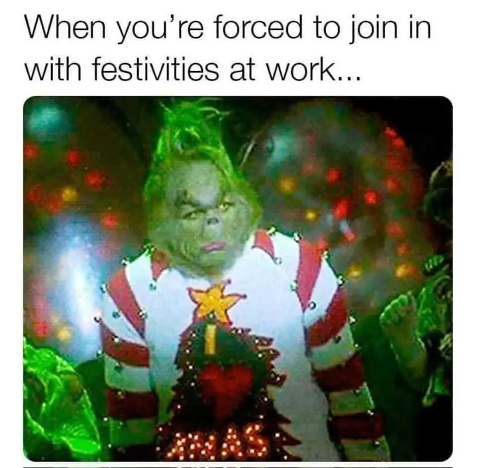 The image shows the green-skinned Grinch wearing a red-and-white striped Christmas sweater with a lit tree and star design…