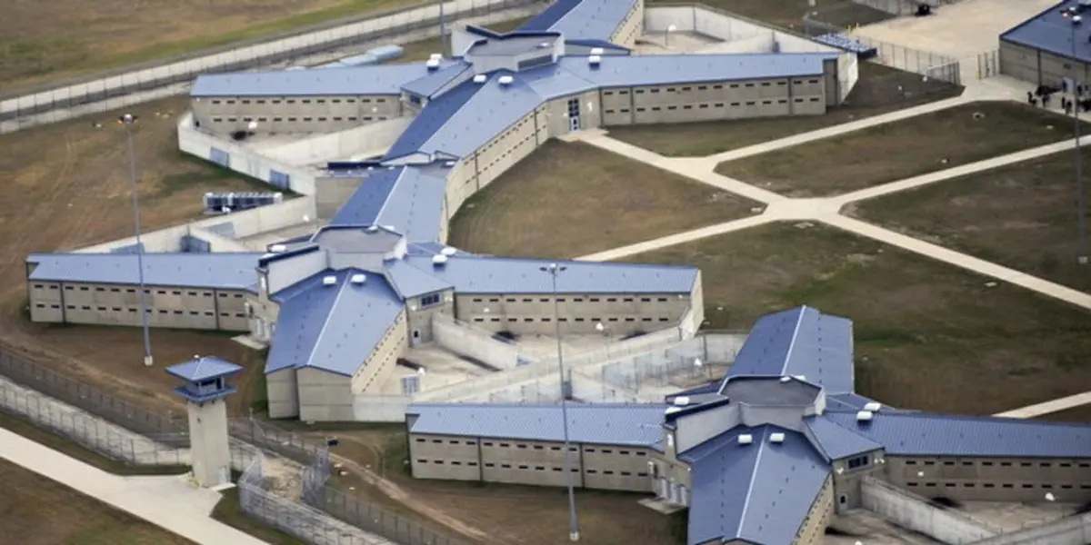 an aerial view of a large, star-shaped prison complex with multiple wings, high fences, and watchtowers. the overlaid text…