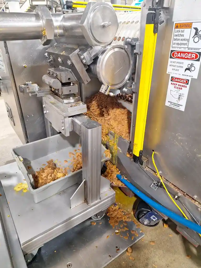 A close-up photo of a large industrial machine with safety warning labels, including one that says 'DANGER KEEP HANDS CLEAR…