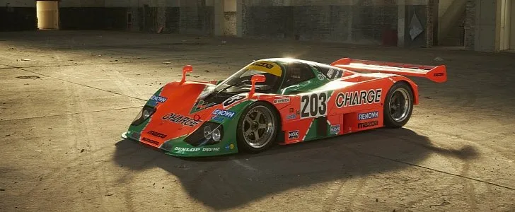 A vintage orange and green race car with the number 203 and 'CHARGE' written on its side is parked in a dusty, abandoned…