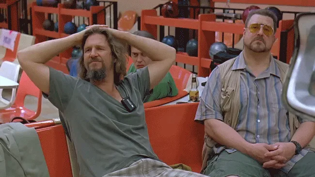 The image shows a split-screen meme with two men in a bowling alley. The man on the left, with long hair and a beard, has…