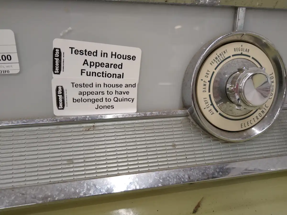 A close-up of a vintage washing machine control panel with a chrome dial labeled 'AIR FLUFF', 'DAMP DRY', 'REGULAR'…