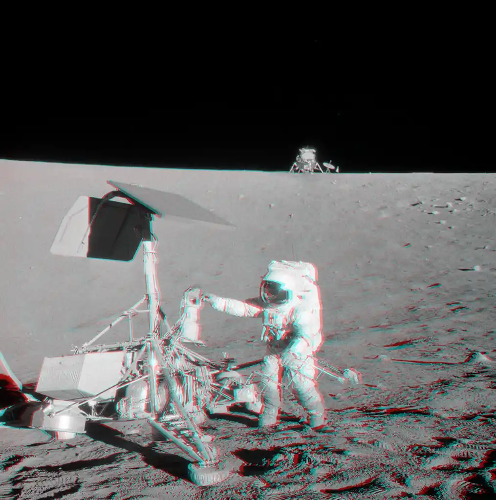 A red-and-blue anaglyph 3D effect image of an astronaut on the moon, interacting with a lunar rover. In the background, the…
