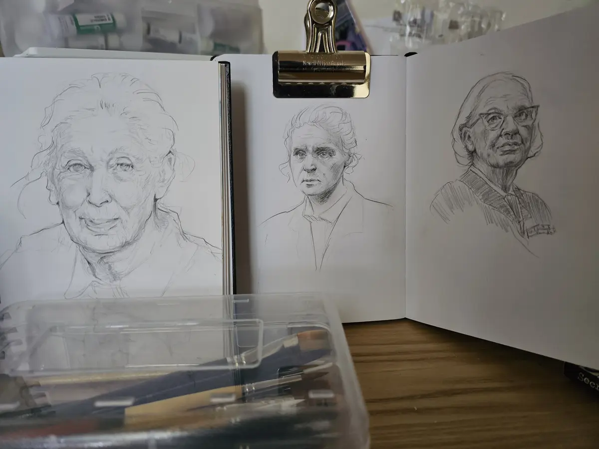 Three pencil sketches of an elderly woman are displayed in an open sketchbook, showing progressive stages of a portrait…