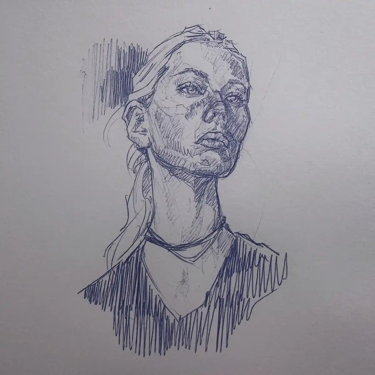A blue ink sketch on white paper depicts a woman's head and shoulders, rendered with expressive, sketchy lines. Her face is…