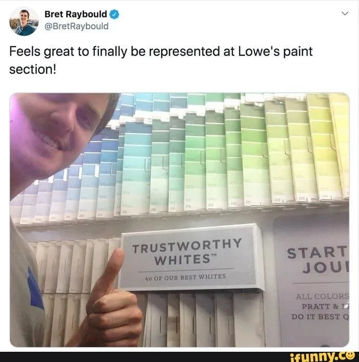 A man with a wide smile and a thumbs-up stands in front of a wall of paint swatches at Lowe's. The swatches show a gradient…