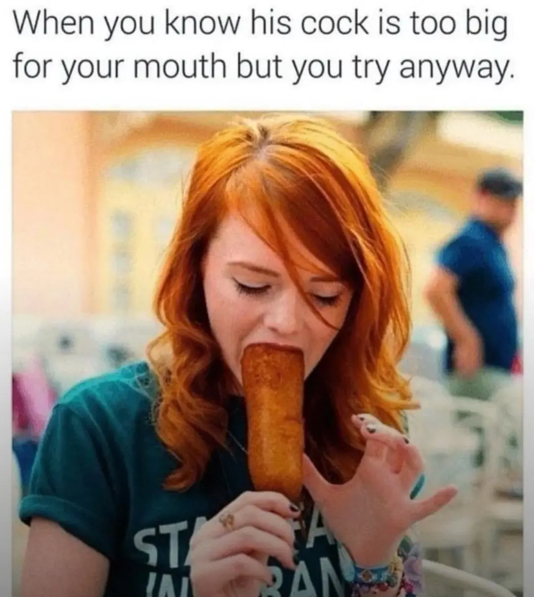A woman with red hair is shown eating a large corn dog, holding it with both hands and biting into it. The overlaid text…