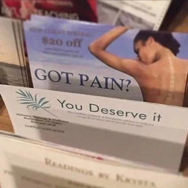 A close-up photo of a massage coupon in a rack, featuring a shirtless man stretching with a beach background. The coupon…