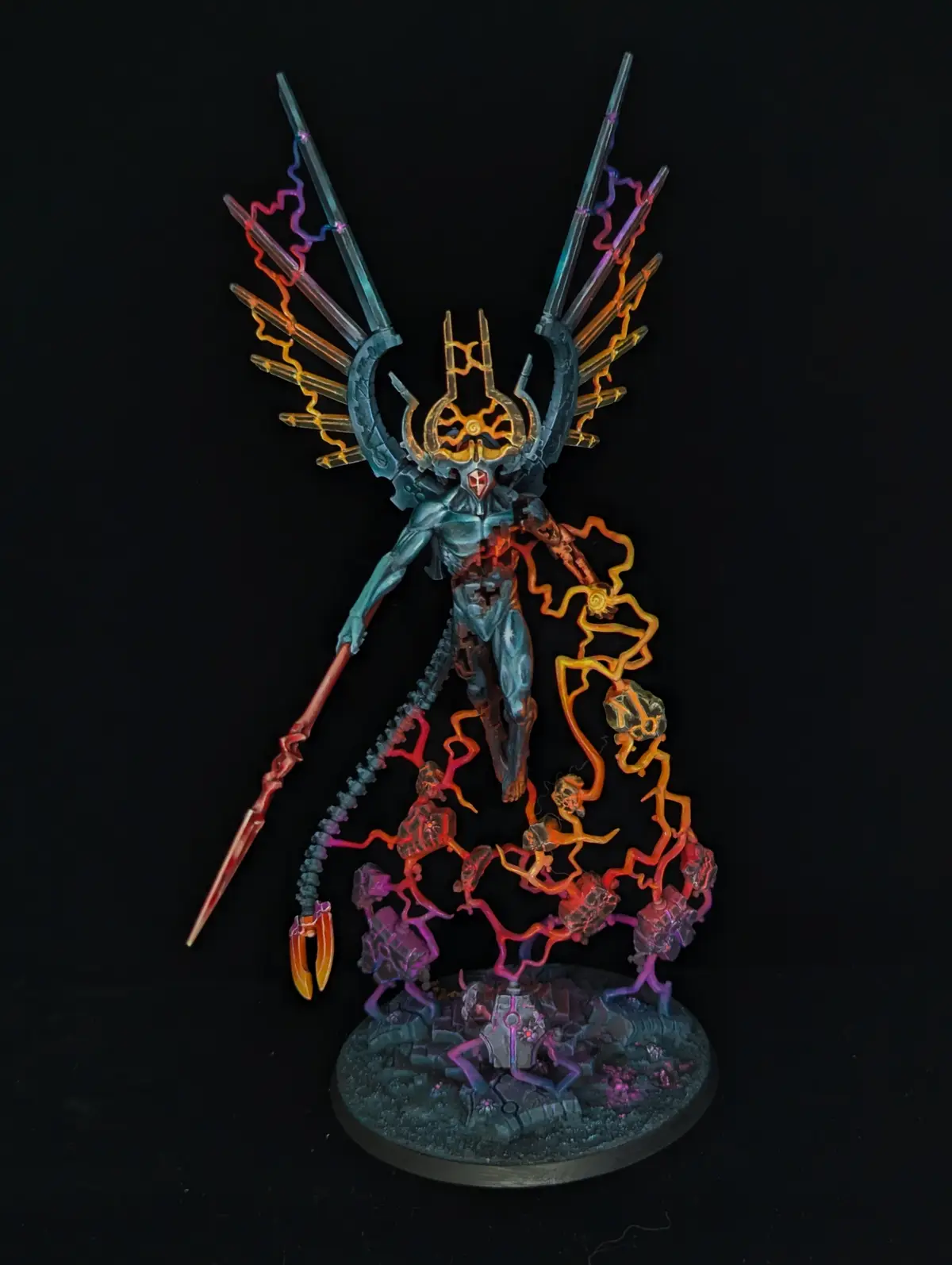 A highly detailed, painted miniature of a demonic or angelic figure with glowing, multi-colored energy tendrils and spikes…