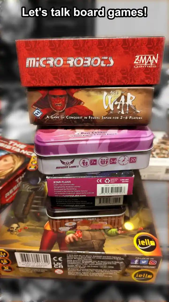 A stack of five different board game boxes is shown, including 'Micro Robots', 'Age of War', 'Star Fluxx', and 'Game Night'…