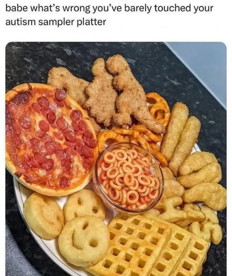 A white platter holds a large variety of kid-friendly foods including a pepperoni pizza, dinosaur-shaped chicken nuggets…