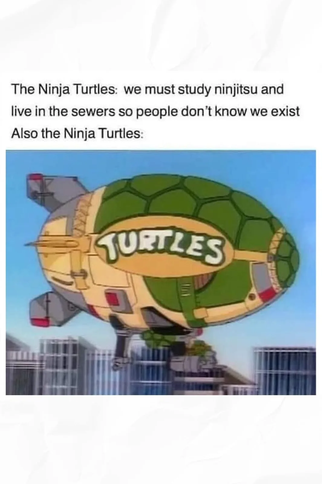 The image shows a large, cartoonish airship shaped like a turtle shell with the word 'TURTLES' written on it, flying over a…