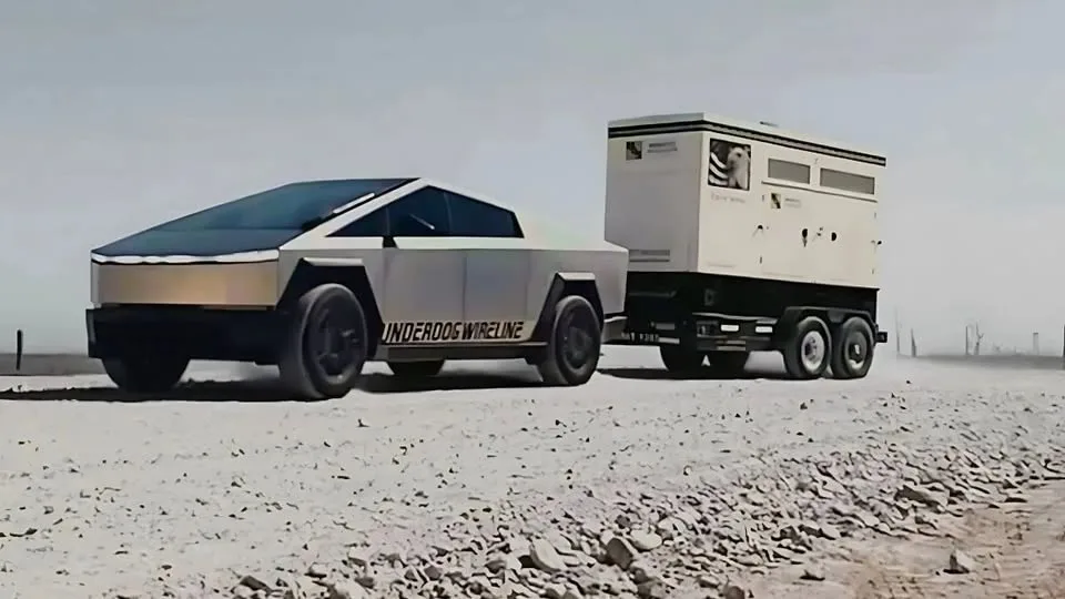A silver Tesla Cybertruck is towing a large white trailer across a barren, rocky desert landscape. The side of the truck has…