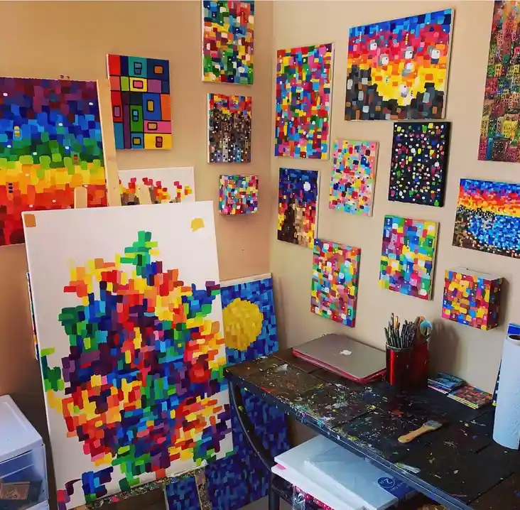 A vibrant artist's studio filled with numerous colorful paintings made of small, distinct square pixels, hanging on the…