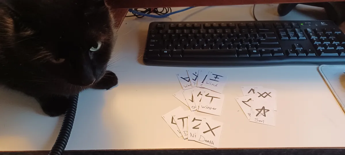 A black cat with green eyes stares intently at a desk where several handwritten cards are scattered near a keyboard. The…