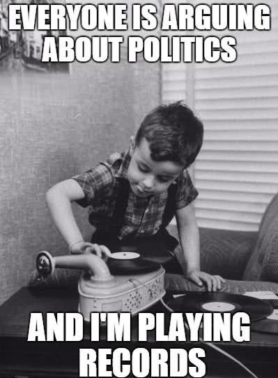 A black-and-white photo shows a young boy in a plaid shirt and overalls leaning over a vintage record player, placing a…