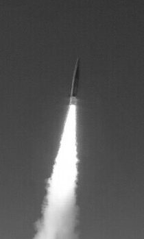 A black and white photo shows a missile ascending into the sky, leaving a bright, thick smoke trail behind it. Overlaid text…