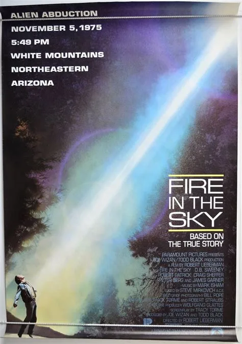 A movie poster for 'Fire in the Sky' shows a person walking away from a bright, glowing beam of light descending from the…