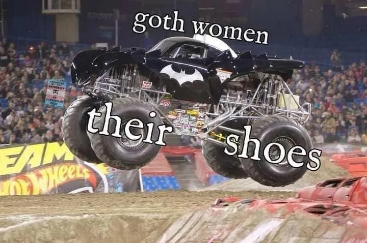 A black Batman-themed monster truck is airborne over a dirt track, with a crowd in the background. The text 'goth women' is…