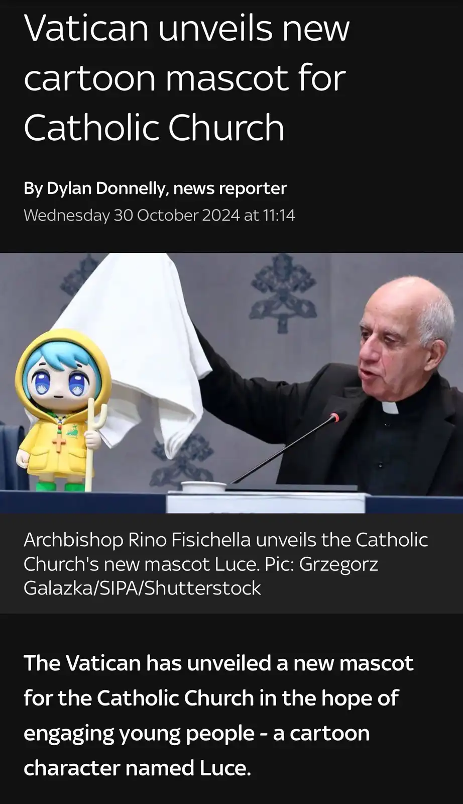 A man in clerical attire, identified as Archbishop Rino Fisichella, is shown at a podium unveiling a cartoon character. He…