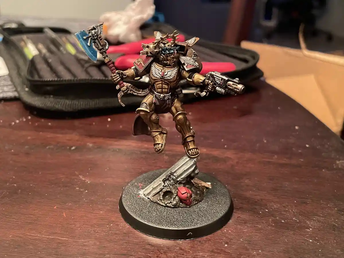 A heavily painted miniature of a fantasy warrior, likely from Warhammer 40k, stands on a circular base with a broken sword…