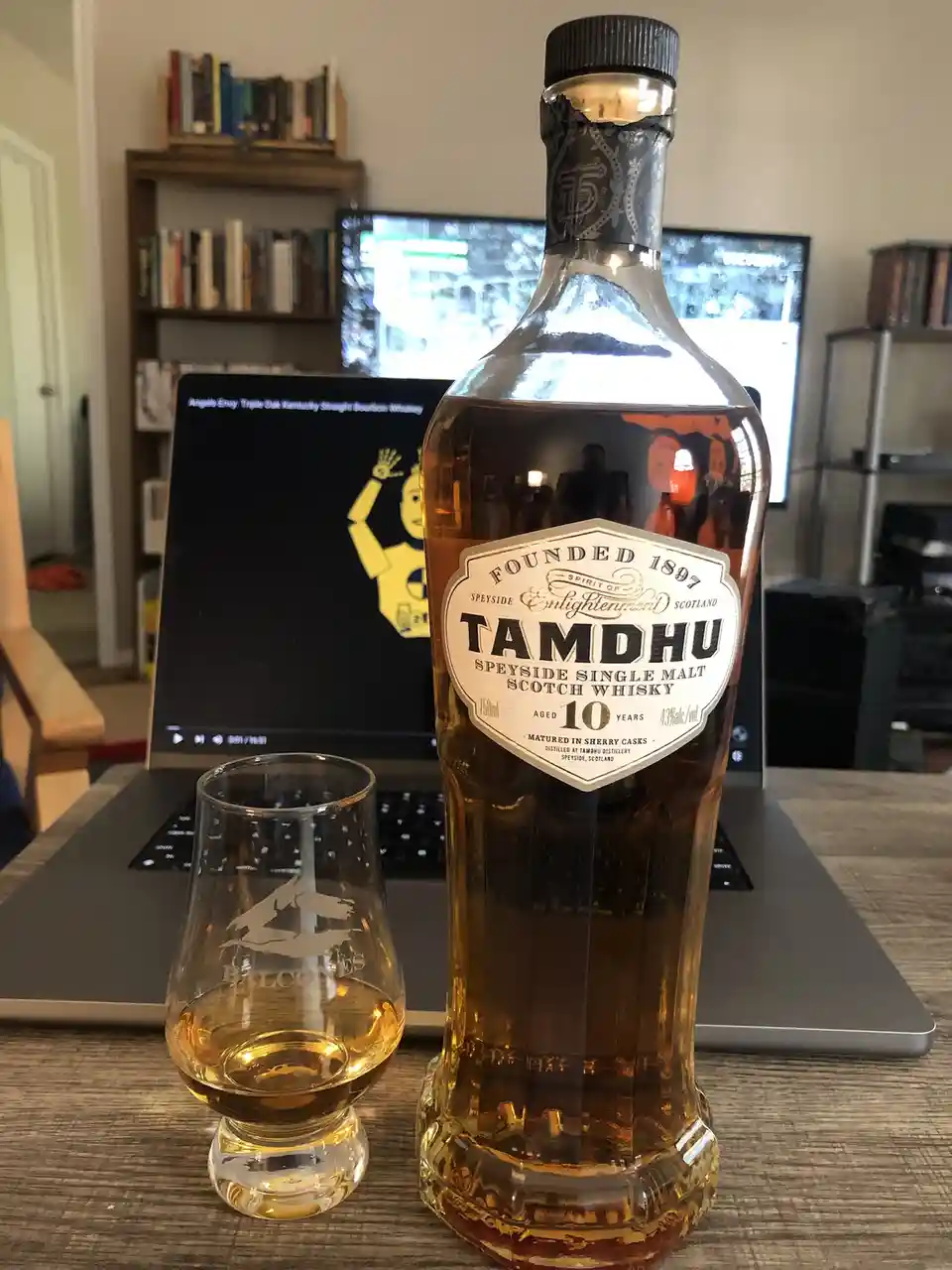 A bottle of Tamdhu 10-year-old Speyside single malt scotch whisky sits on a wooden table next to a tasting glass with a…