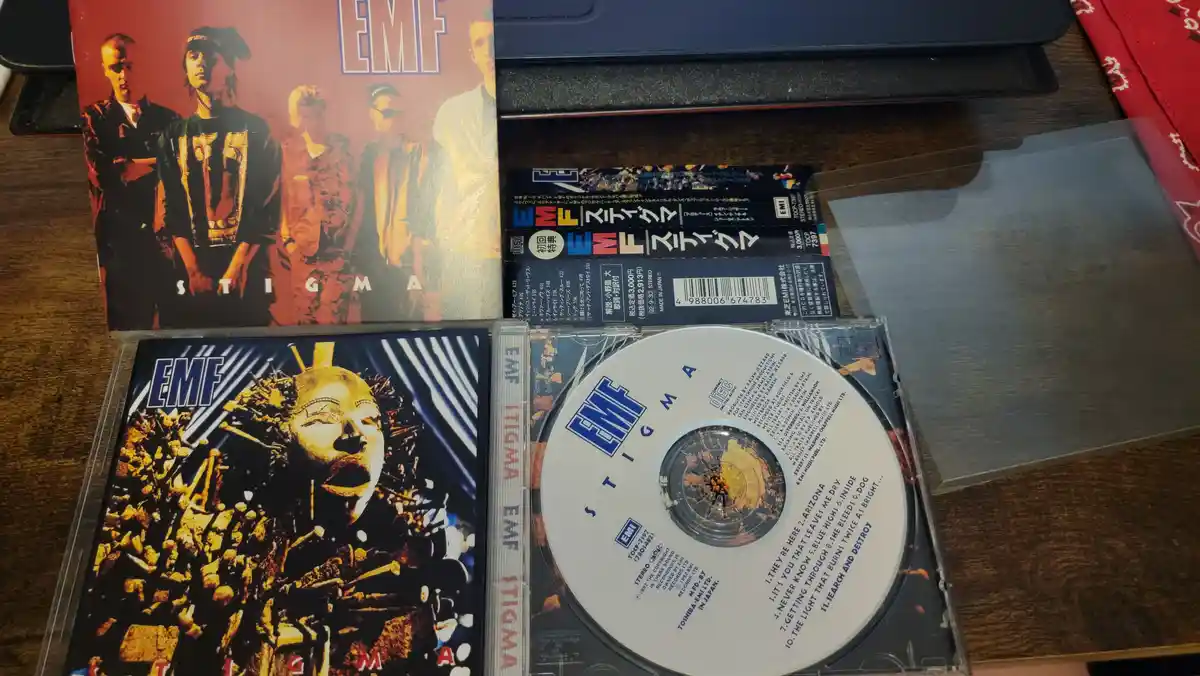 A photo of the Japanese release of the 1992 EMF album 'Stigma', showing the CD, jewel case, and booklet with Japanese text…
