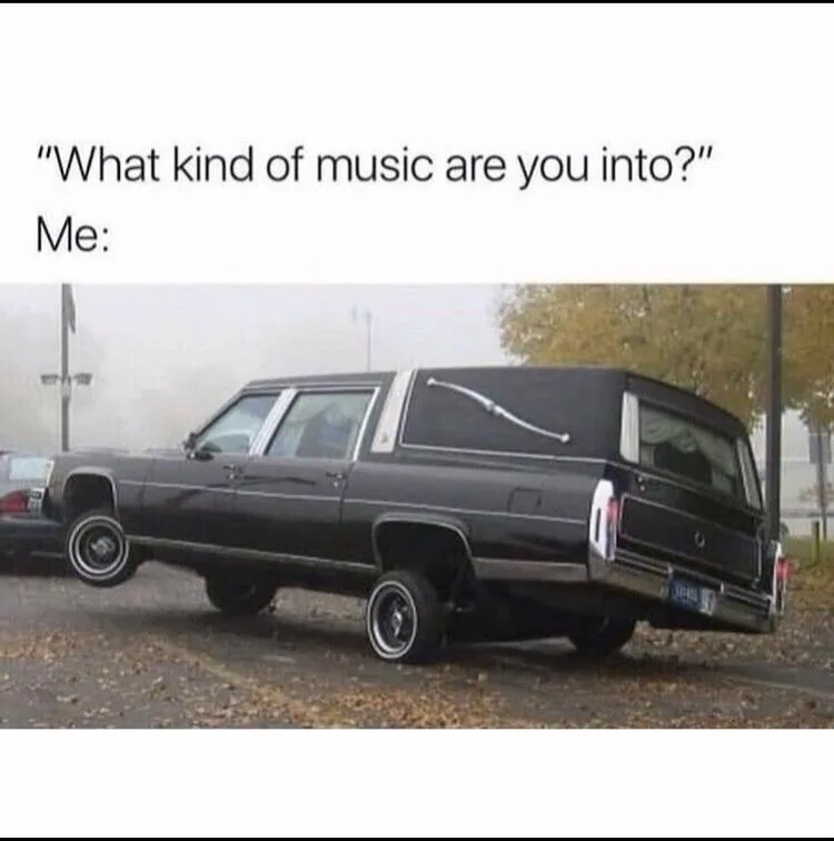 A black, lifted, vintage station wagon is parked at an extreme angle, tilted so its front wheels are off the ground and its…