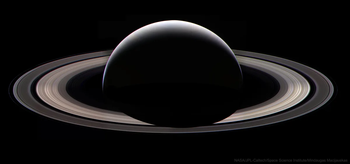 The image shows the planet Saturn with its iconic rings, but the planet itself is rendered as a perfectly black, featureless…