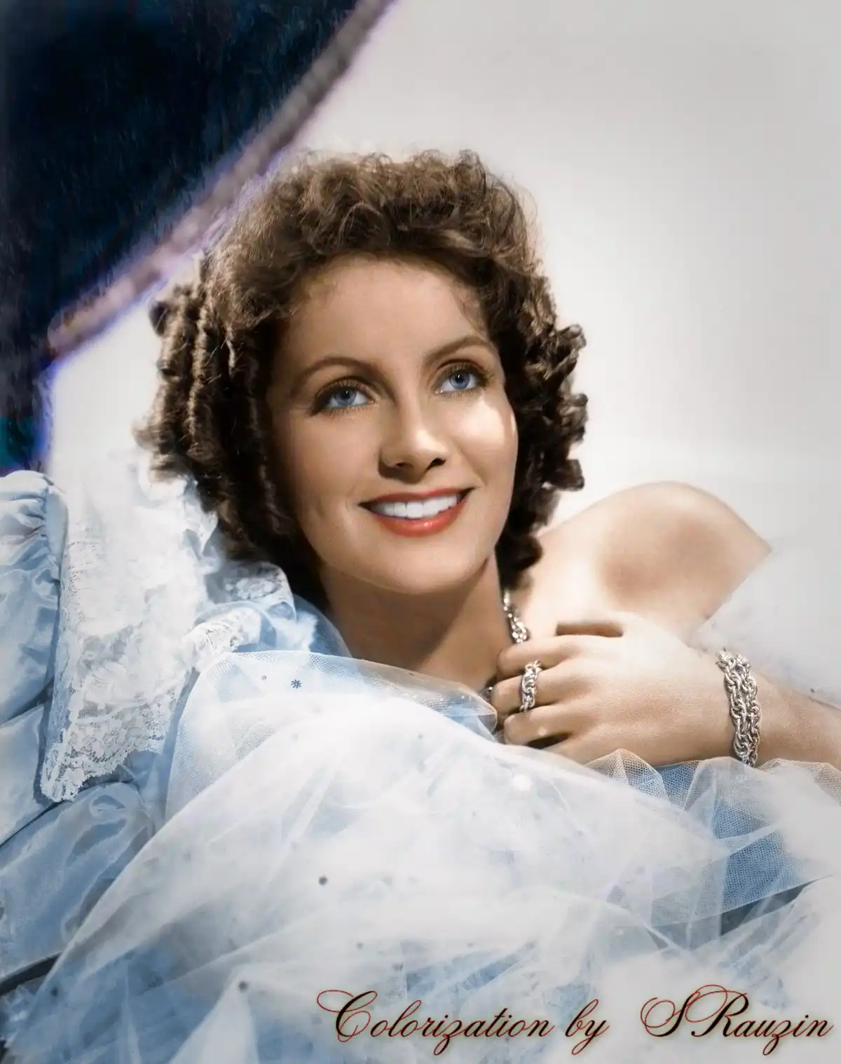 A colorized vintage portrait of a smiling woman with curly brown hair and blue eyes, wearing a light blue dress with lace…