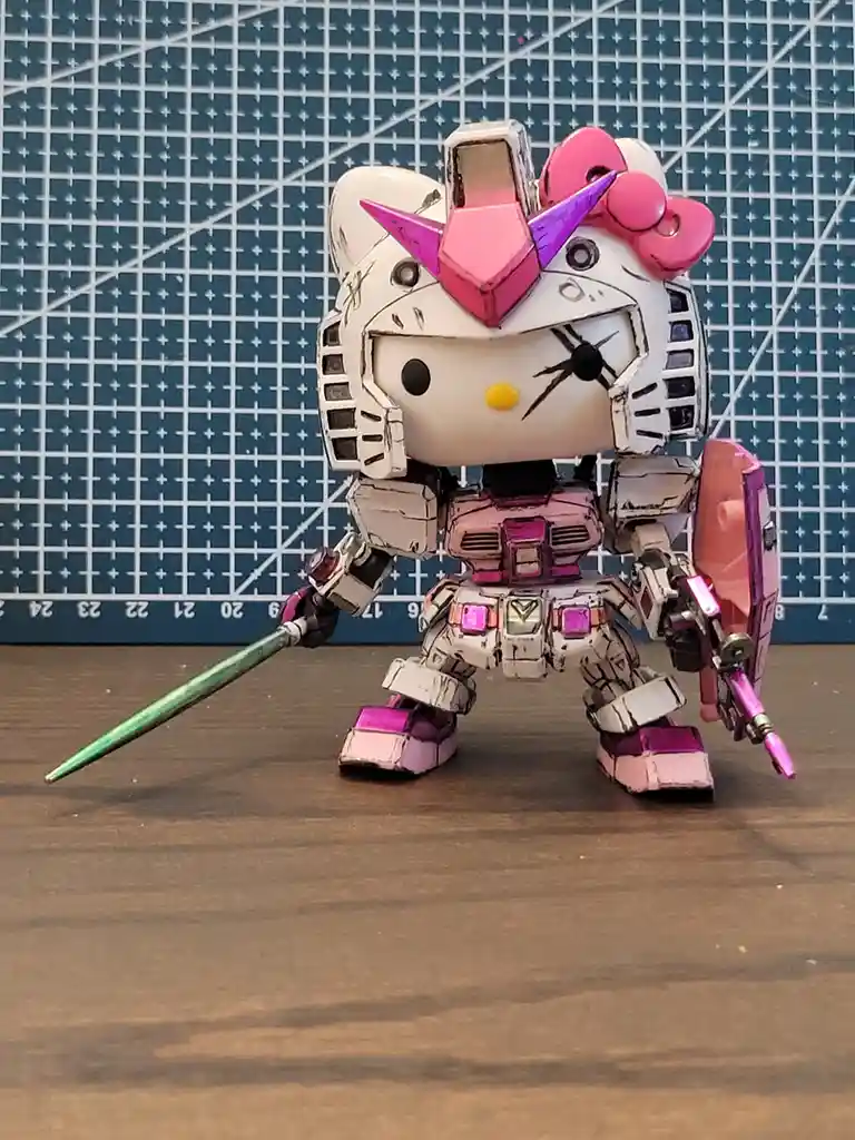A custom-painted model of a Gundam-style robot with the head of Hello Kitty, featuring her iconic pink bow and yellow nose…