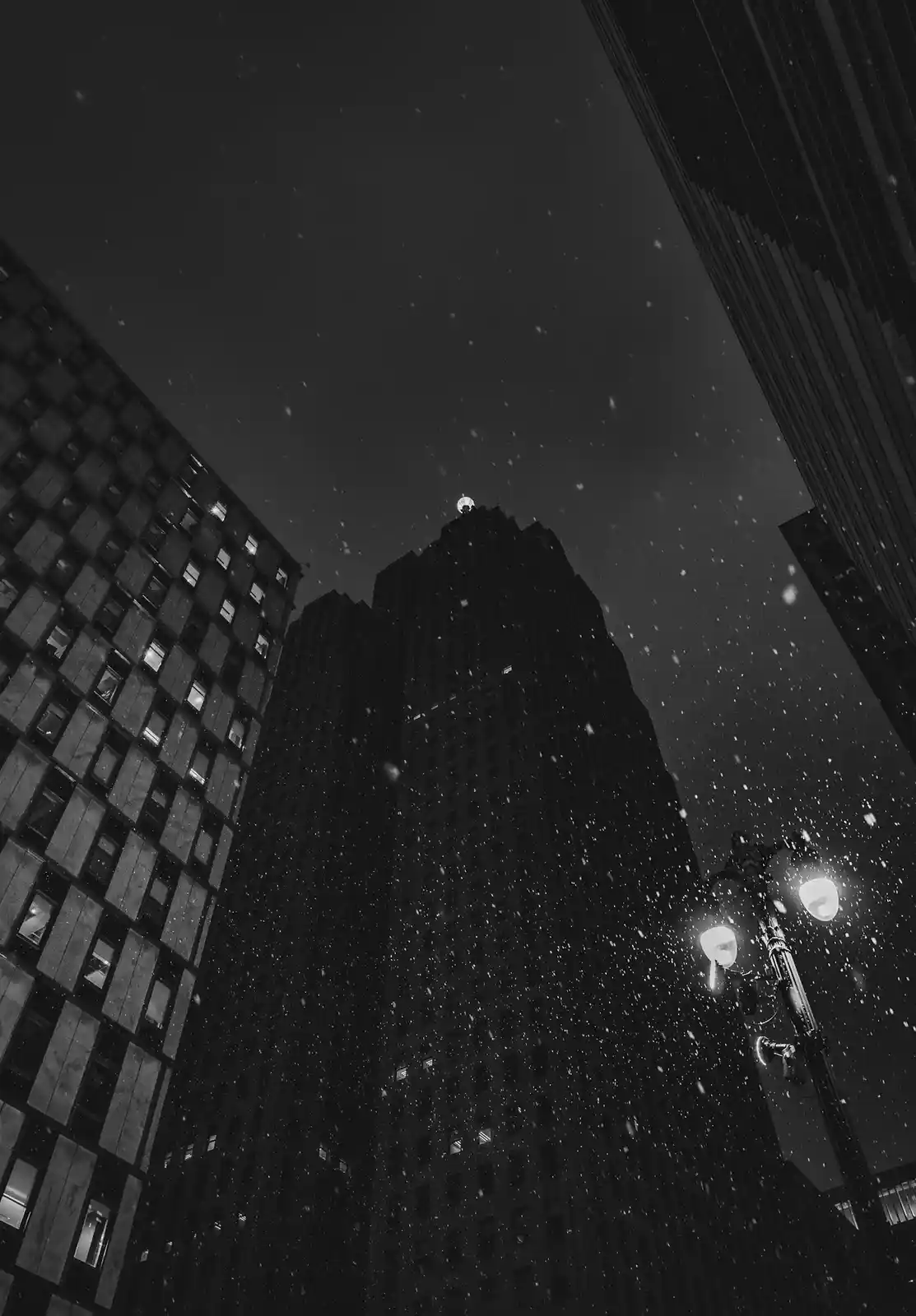 A black-and-white photo shows a snowy night in a city with tall buildings and a lit streetlamp, overlaid with the text 'i'm…
