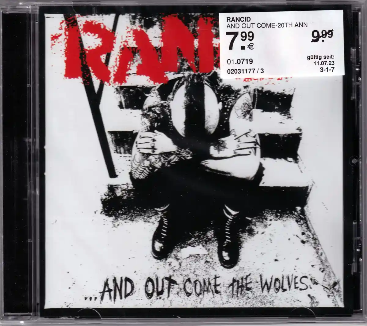 A CD cover for Rancid's album '...And Out Come the Wolves' featuring a black-and-white illustration of a person sitting on a…