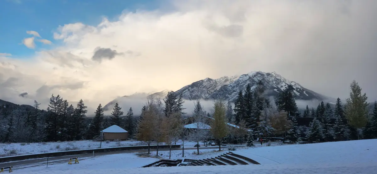 A snowy landscape with mountains, trees, and buildings under a cloudy sky, overlaid with the text 'i'm not lazy, i'm in…